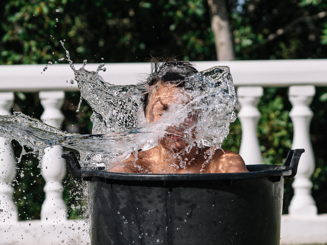 person taking a cold plunge with water splashing in front of face