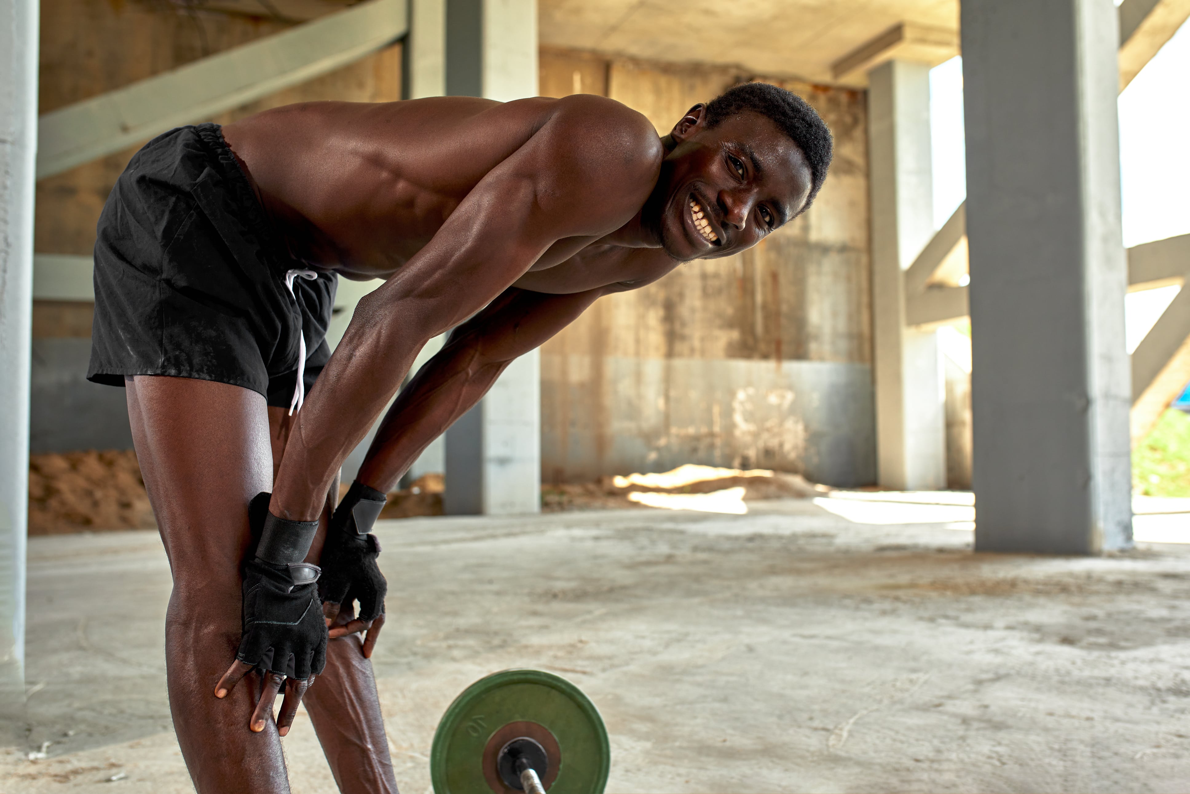 an athletic person lifting weights outside and smiling
