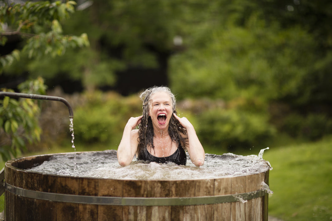 a female cold plunging in tub in yard