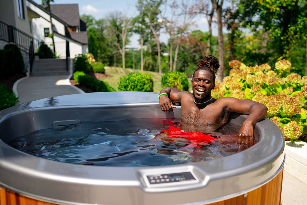 Man relaxing in a Coldtub cold plunge tub in a backyard setting.